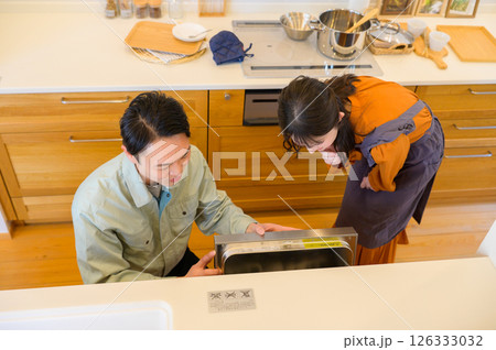 キッチンの設備を点検する作業服の日本人男性と女性 キッチンの設備を点検する作業服の日本人男性と女性 126333032