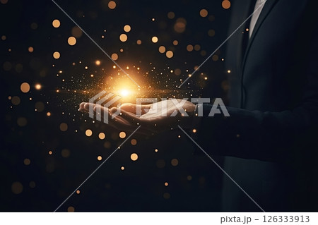 Businessman holding glowing light and golden particles in open hands 126333913