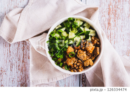 Close up of buckwheat porridge with meat, cucumber and chives in a bowl on the table top view 126334474