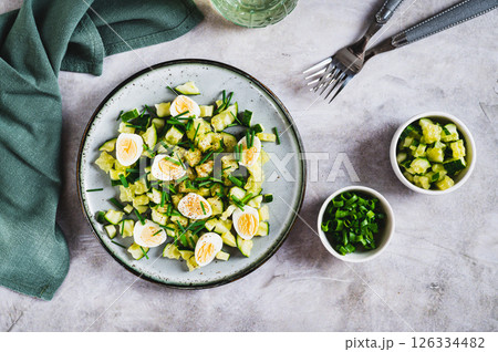 Fresh salad of cucumbers, quail eggs and green onions on a plate on the table top view 126334482