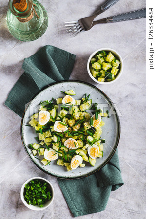 Appetizing mix of cucumbers, eggs and chives on a plate on the table top and vertical view 126334484