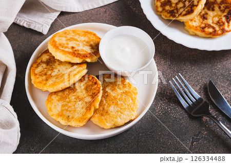 Appetizing potato fritters and sour cream on a plate on the table 126334488
