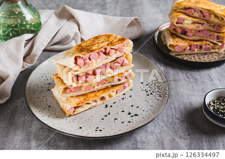 Crispy envelopes with sausage and cheese in flat bread on a plate on the table 126334497