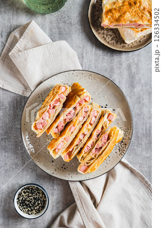 Crispy envelopes with sausage and cheese in flat bread on a plate top and vertical view Crispy envelopes with sausage and cheese in flat bread on a plate top and vertical view 126334502