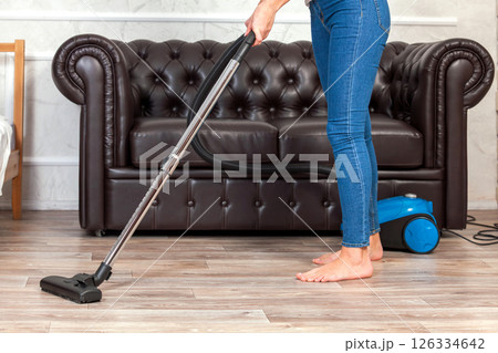 Close-up of a woman cleaning the floor with a vacuum cleaner 126334642