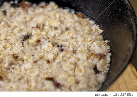 porridge with dried berries and fruits in a black bowl , cooking instant oatmeal porridge porridge with dried berries and fruits in a black bowl , cooking instant oatmeal porridge 126334883