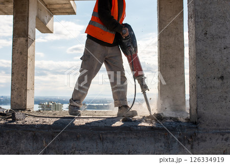 Construction worker using jackhammer to drill concrete floor. Construction worker using jackhammer to drill concrete floor. 126334919