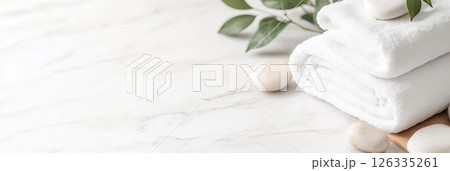 Spa concept with white towels and stones on marble surface, serene background 126335261