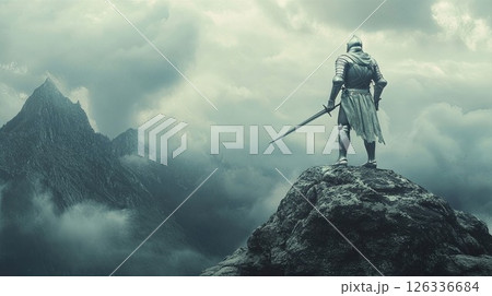 Majestic medieval knight in shining armor stands on rocky cliff overlooking misty mountain valley. Dramatic fantasy scene with castle silhouette, moody cloudy sky, and warrior holding longsword 126336684
