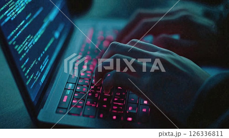 Cybersecurity concept showing hands typing on illuminated keyboard with code visible on screen, dramatic neon lighting creates mysterious tech atmosphere Cybersecurity concept showing hands typing on illuminated keyboard with code visible on screen, dramatic neon lighting creates mysterious tech atmosphere 126336811