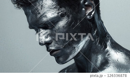Artistic black body paint portrait capturing profile view in monochromatic style. Dramatic beauty photography showcases textured metallic effect with water droplets on skin 126336878