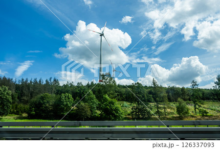 wind turbines against cloudy sky, view from car window 126337093