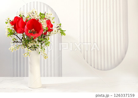 Still life with beautiful spring branches of blooming bird cherry, cherry and red tulips in a vase on an elegant background. Abstract floral composition and banner for the screen, floral holiday card. Still life with beautiful spring branches of blooming bird cherry, cherry and red tulips in a vase on an elegant background. Abstract floral composition and banner for the screen, floral holiday card. 126337159