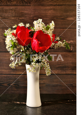 Abstract floral arrangement and banner for screen, Still life with beautiful spring branches of blooming bird cherry, cherry and red tulips in vase on elegant background. Floral holiday card with Abstract floral arrangement and banner for screen, Still life with beautiful spring branches of blooming bird cherry, cherry and red tulips in vase on elegant background. Floral holiday card with 126337164