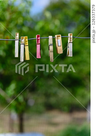 Colorful plastic clothespins hanging on wire outdoors. 126337379