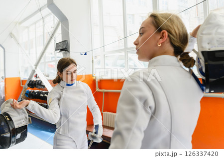 Two female fencers removing masks after match Two female fencers removing masks after match 126337420