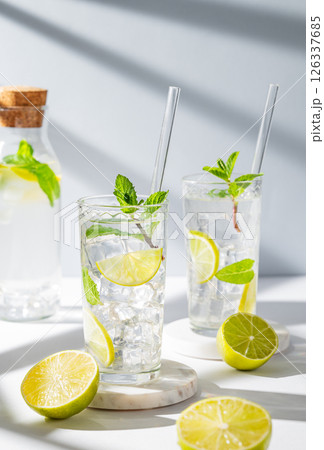 Two glasses mojito cocktail with lime, mint, ice and tube on a light background Two glasses mojito cocktail with lime, mint, ice and tube on a light background 126337685