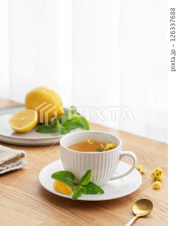 Cup of herbal tea with lemon, honey and mint on wooden tabletop with citrus fruits 126337688