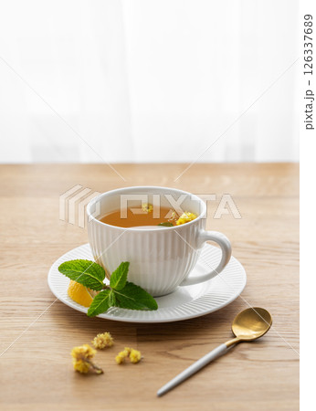 Cup of herbal tea with lemon, honey and mint on wooden tabletop 126337689