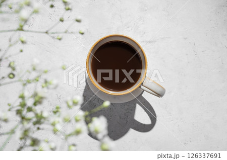 Cup of freshly brewed coffee and bouquet of gypsophila on light textured background Cup of freshly brewed coffee and bouquet of gypsophila on light textured background 126337691