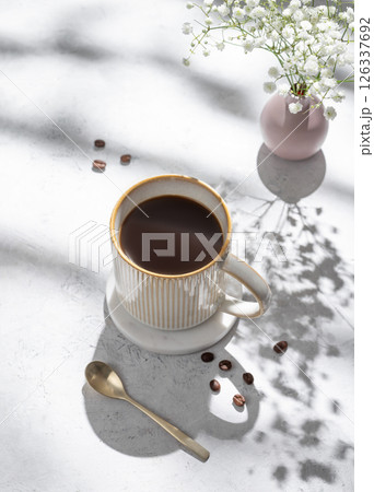 Cup of freshly brewed coffee and bouquet of gypsophila on light textured background 126337692