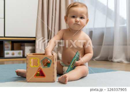 Sweet caucasian baby boy sitting on floor and playing Sweet caucasian baby boy sitting on floor and playing 126337905