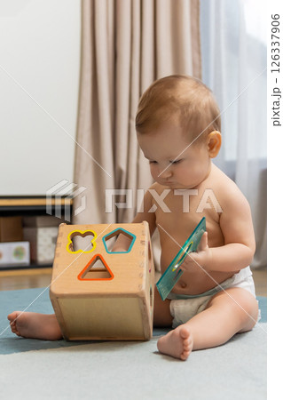 Sweet caucasian baby boy sitting on floor and playing 126337906