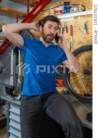 Mechanic speaking on mobile in workshop 126337923