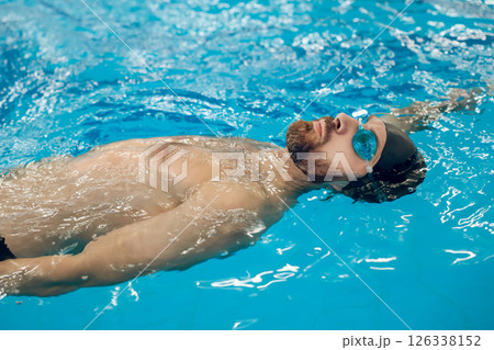 Man in swimming glasses and swimming cap spending time in a pool Man in swimming glasses and swimming cap spending time in a pool 126338152