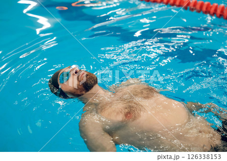 Man in swimming glasses and swimming cap spending time in a pool Man in swimming glasses and swimming cap spending time in a pool 126338153