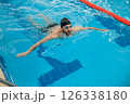 Man in black swimming cap swimming crawl style in the pool 126338180