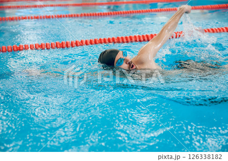 Man in black swimming cap swimming crawl style in the pool 126338182