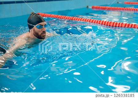 Man in black swimming cap swimming crawl style in the pool 126338185