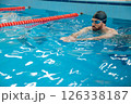 Man in black swimming cap swimming crawl style in the pool 126338187