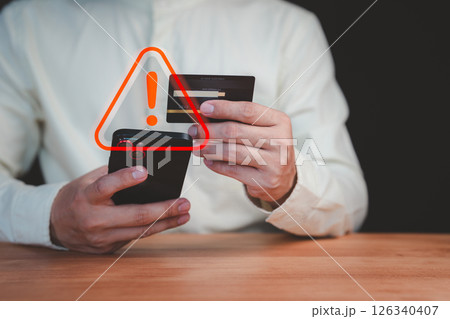 A person holding a credit card and smartphone with a red warning sign overlay, symbolizing online scams, fraud, security risks, and financial caution in digital transactions. A person holding a credit card and smartphone with a red warning sign overlay, symbolizing online scams, fraud, security risks, and financial caution in digital transactions. 126340407