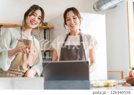 タブレットを見ながらキッチンで料理をする女性 タブレットを見ながらキッチンで料理をする女性 126340556