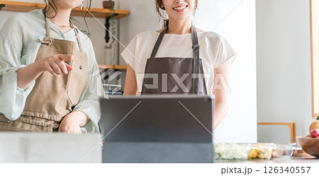 タブレットを見ながらキッチンで料理をする女性 126340557