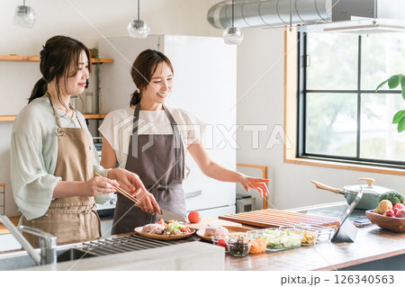 料理教室・クッキングスクールで料理を教える講師の女性と生徒の女性 料理教室・クッキングスクールで料理を教える講師の女性と生徒の女性 126340563