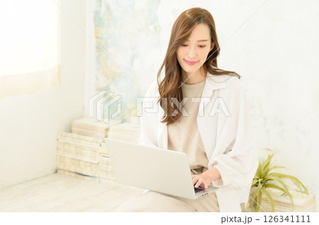 ノートパソコンを膝上に置いて操作する女性 ノートパソコンを膝上に置いて操作する女性 126341111