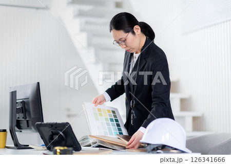 建材と資料をひろげて作業をする建設会社の女性社員 建材と資料をひろげて作業をする建設会社の女性社員 126341666