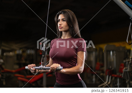 fitness enthusiast engages in strength training at gym in the evening focused on cable workout to target upper body muscles and improve overall fitness. 126341915