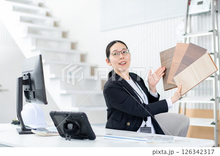 フローリングのサンプルをもって説明するハウスメーカーの女性社員 フローリングのサンプルをもって説明するハウスメーカーの女性社員 126342317