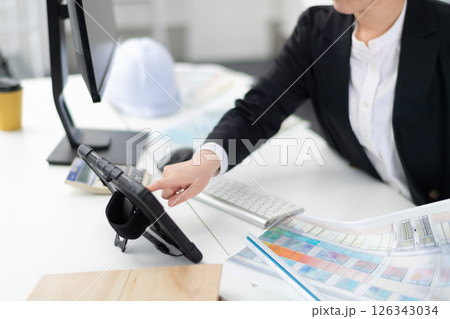 タブレット端末を操作する建設会社の女性社員の手元 126343034