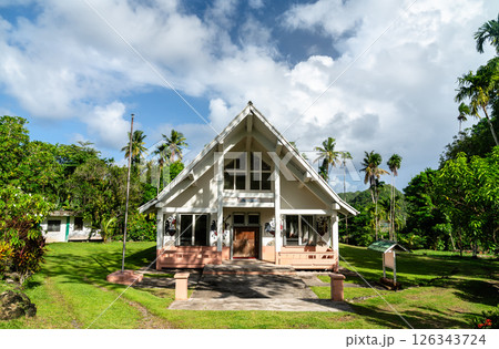 Traditional Palauan meeting house Bai ra Mlengl, nestled in lush tropical surroundings in Airai. The building features a steep gabled roof and distinctive painted motifs, standing peacefully amid palm 126343724