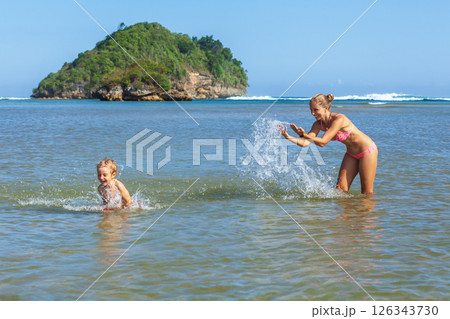Happy family - mother, kids  at amazing tropical beach with blue ocean . Active parents and people outdoor activity on tropical summer vacations with children 126343730