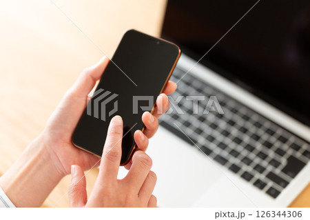 スマホを持つミドル女性の手元 126344306