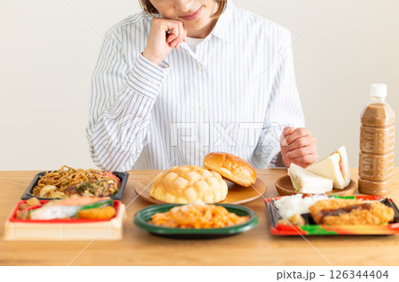 たくさんの食べ物を前に悩むミドル女性 126344404