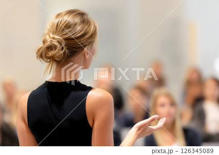 Female speaker giving a talk on corporate business conference. Unrecognizable people in audience at conference hall. Business and Entrepreneurship event. Female speaker giving a talk on corporate business conference. Unrecognizable people in audience at conference hall. Business and Entrepreneurship event. 126345089