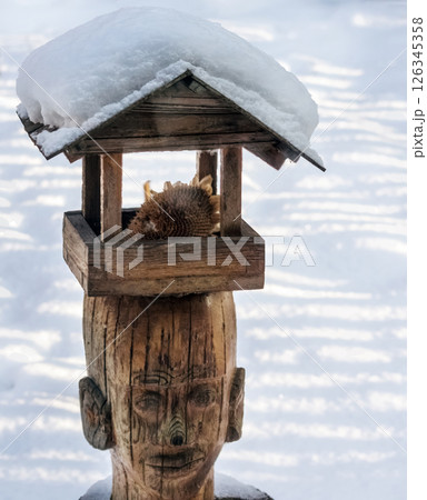 Wooden bird feeder in the snow in the park in winter. DIY wooden crafts. 126345358
