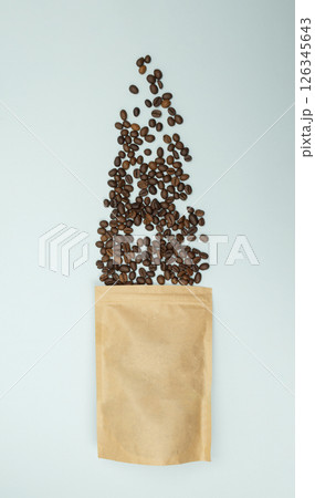 Scattered coffee beans from kraft paper bag, blue background, Top view. Flat lay 126345643